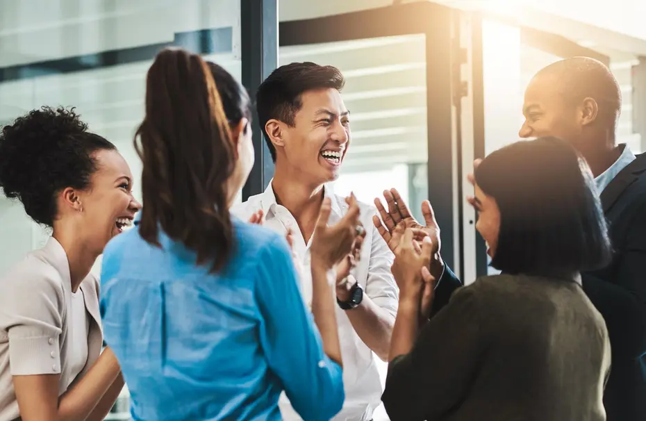 Un groupe de six personnes souriantes, représentant la diversité, est rassemblé dans un espace lumineux. Elles se congratulent et échangent des rires, créant une atmosphère d'amitié et de camaraderie.